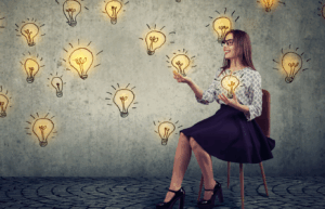 Woman smiling and sitting in a chair with lightbulbs floating around