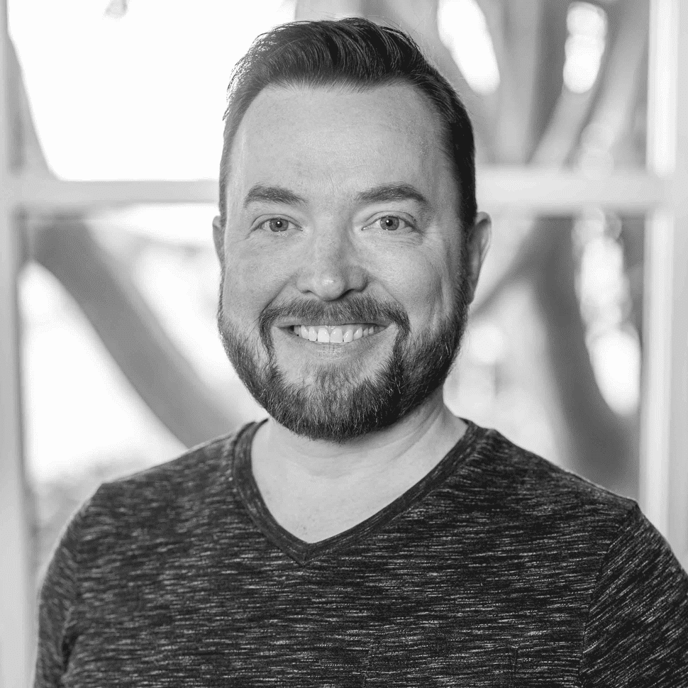 Headshot of Andy Reynolds smiling in black and white