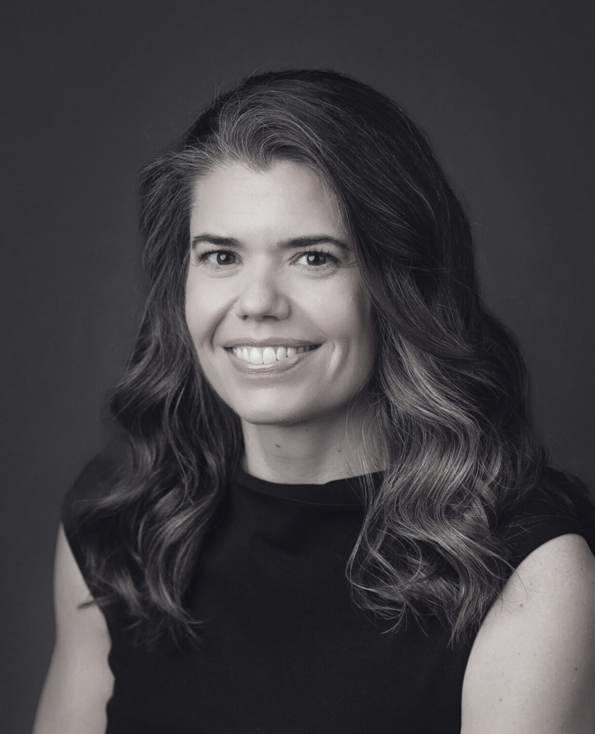 Headshot of Kim Melville-Smith smiling in black and white